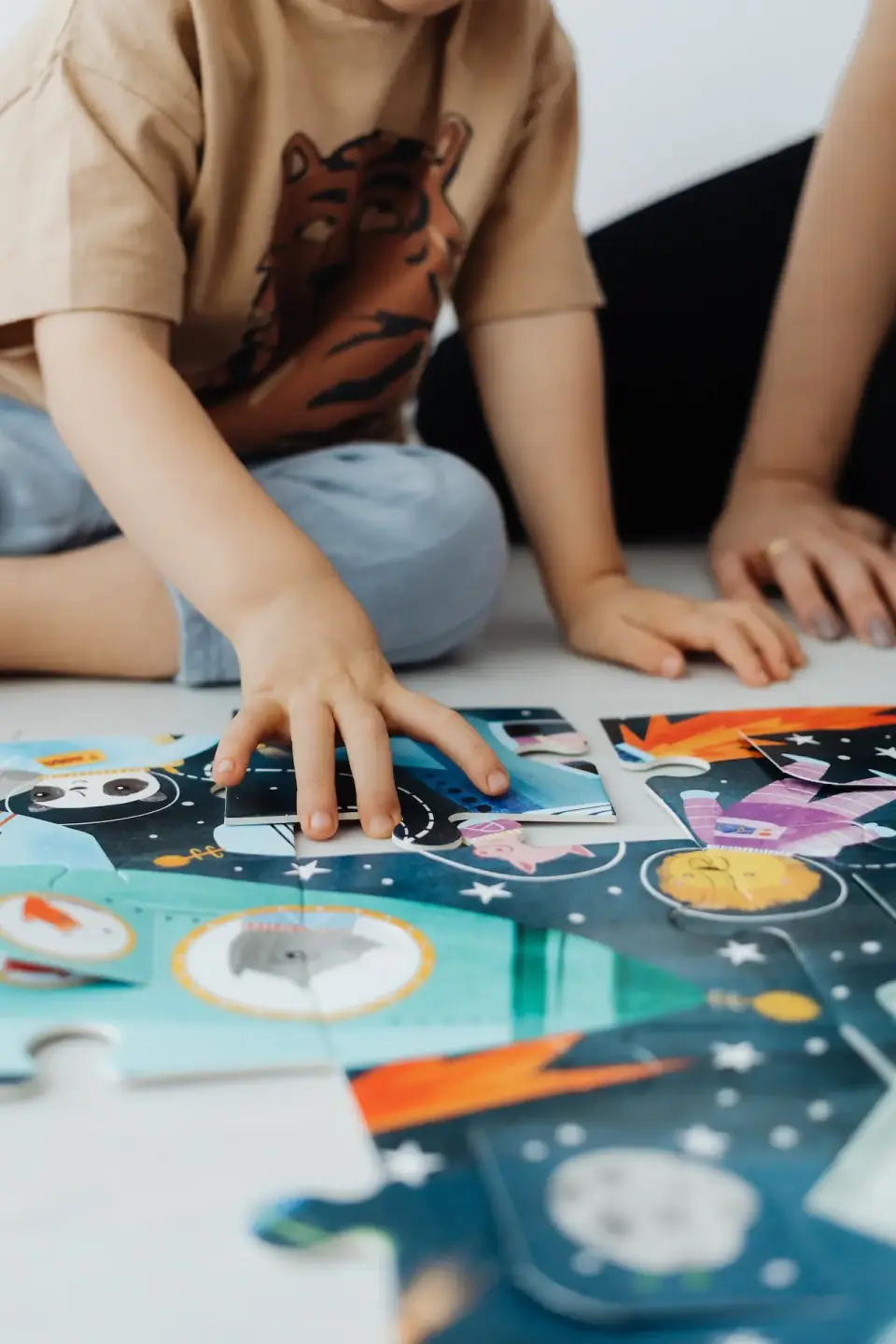 Kinderhände legen ein Puzzle auf dem Boden