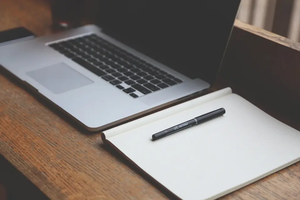 Schreibtisch mit Notizbuch und Laptop