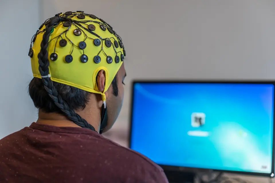 Person mit EEG-Haube vor einem Bildschirm beim Neurofeedback